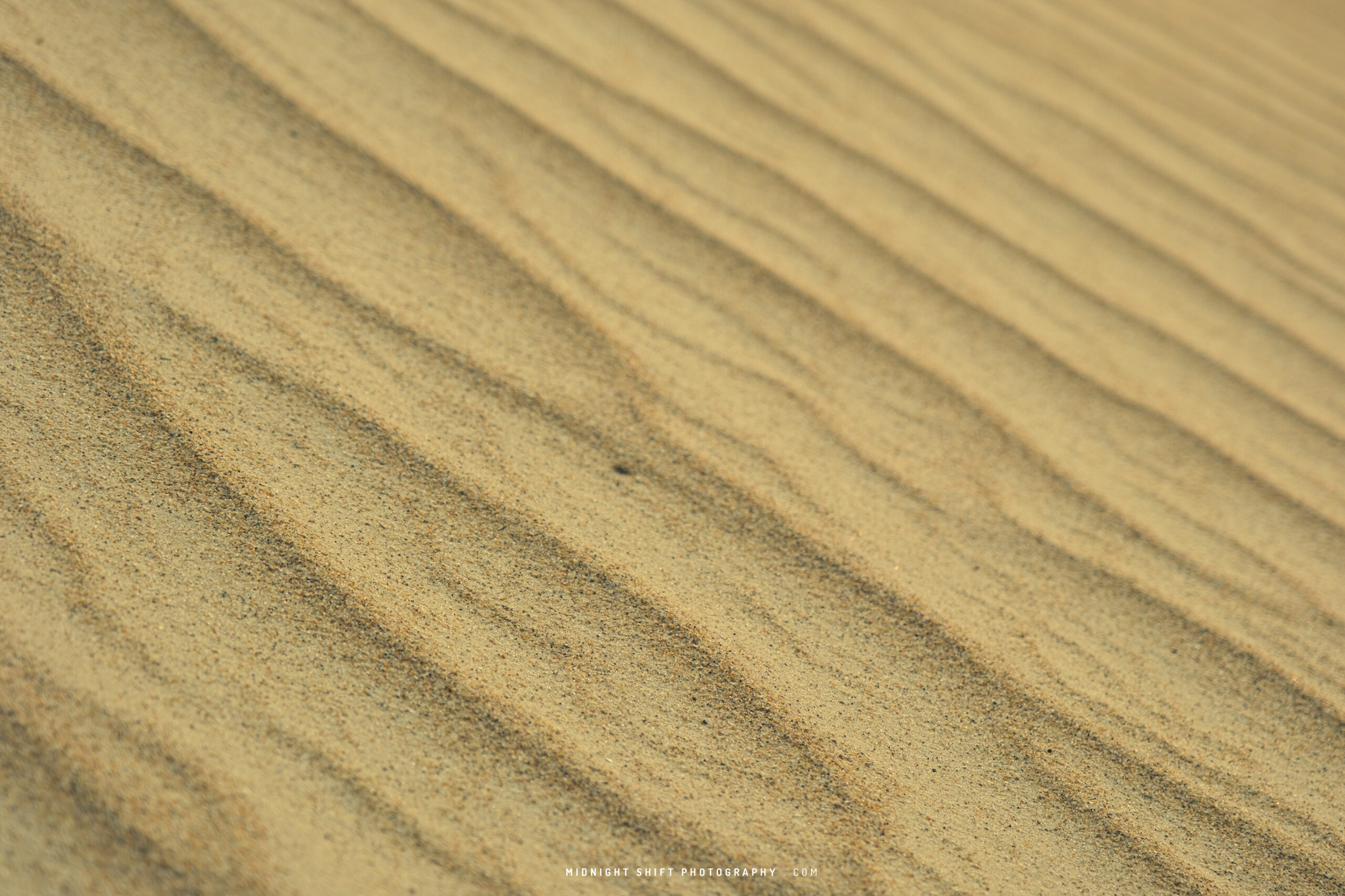 Waves of sand on a sand dune photographed at an angle.