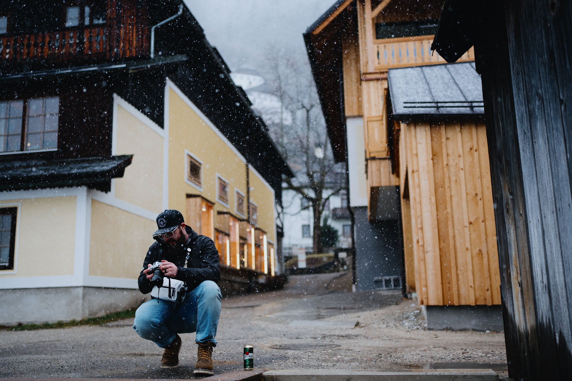 Jeff Golenski looks at his camera as it snows on a street in Halstatt Austria